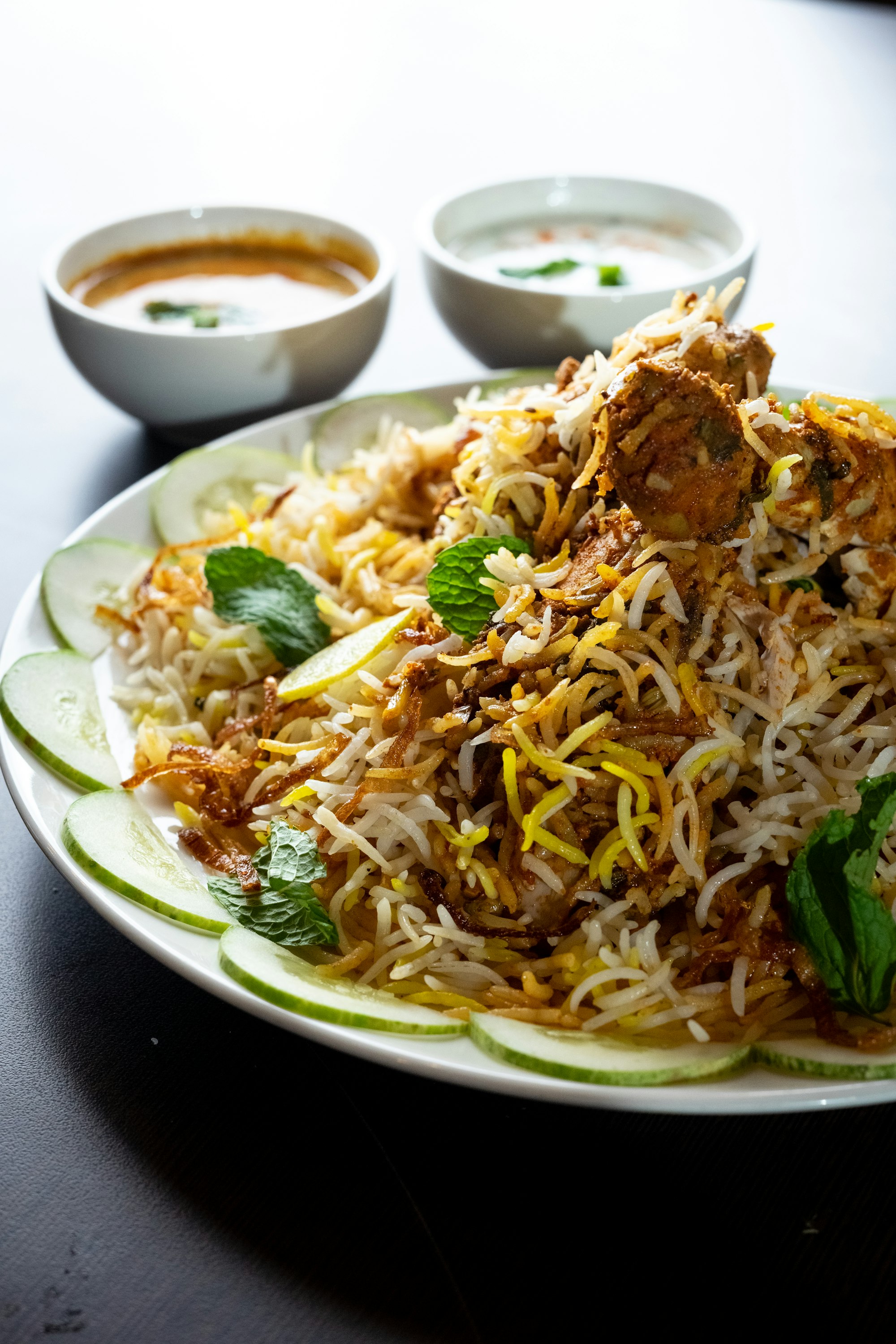 Plate of Hyderabadi chicken dum biryani with raita and salan